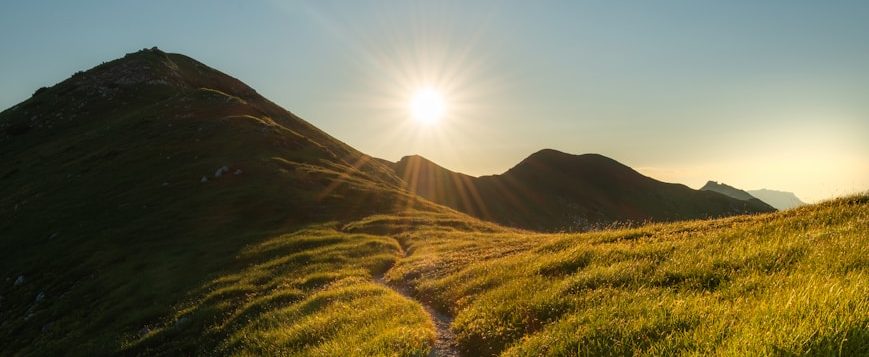 Naturcoaching, Change Management, Veränderung ein schmaler Pfad auf einem Bergrücken im Gegenlicht der Sonne