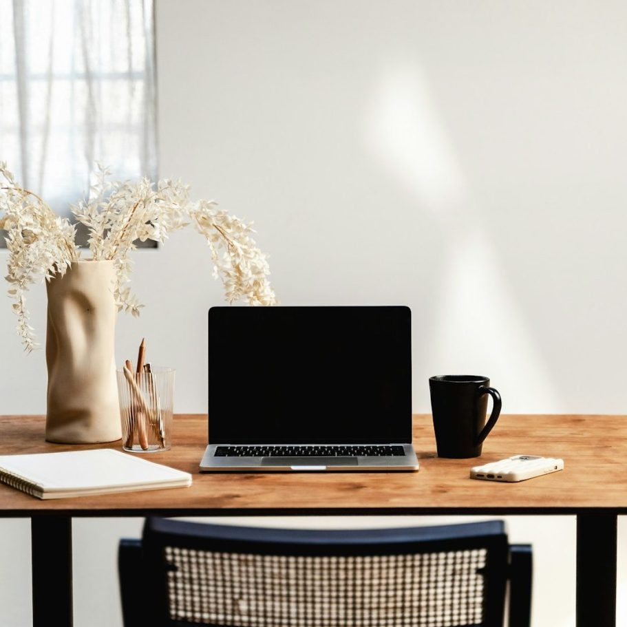 Individuelles Online Coaching ein Laptop steht auf einem Schreibtisch, daneben eine Tasse und Blumen